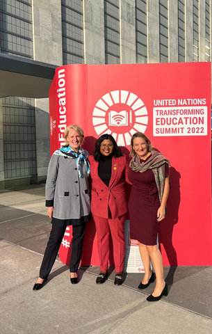 Anjum standing with two women in front of a placard for the UN Transforming Education Summit 2022