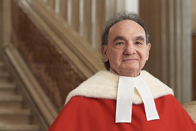 Michael Moldaver stands in front of a stone staircase, wearing his Supreme Court of Canada robes.