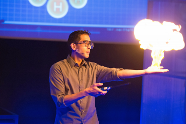 Man holding a fireball above his hand at a science demonstration