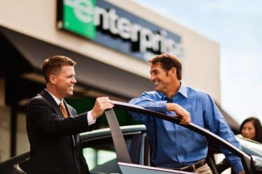 Man smiling as an Enterprise car rental employee shows him his rental car