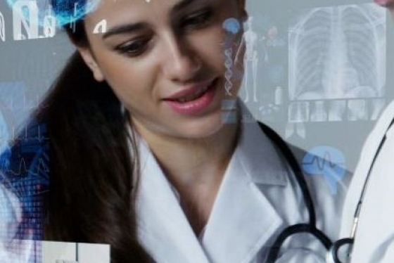 Woman in white labcoat and stethoscope with another person looking at tablet