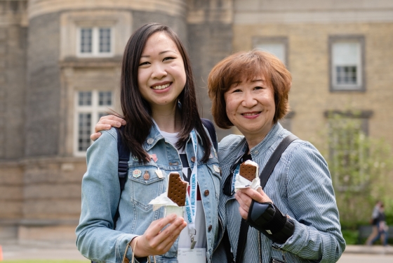 Two alumni posing together with ice cream in their hands.