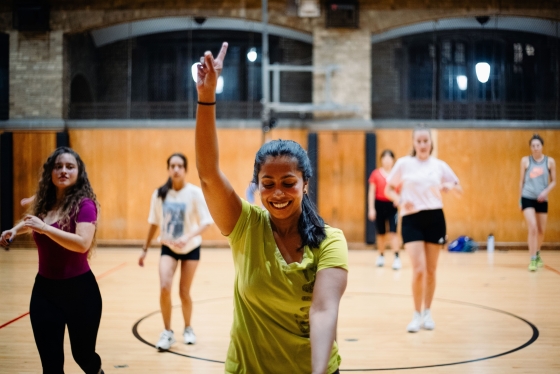 Sandani Hapuhennedige smiling in a gymnasium as she teaches a fitness class to others.
