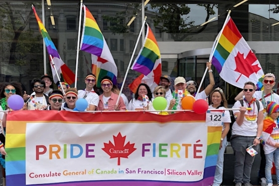 People celebrating Pride, holding a banner that reads "Pride - Fierte" and "Consulate General Consulate General of Canada in San Francisco | Silicon Valley"