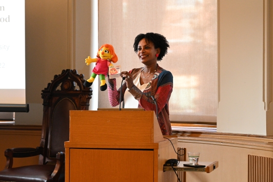 Rhonda McEwen stands at a podium with her puppet Julia