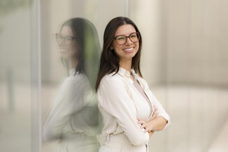 Thaisa stands with her arms crossed, smiling