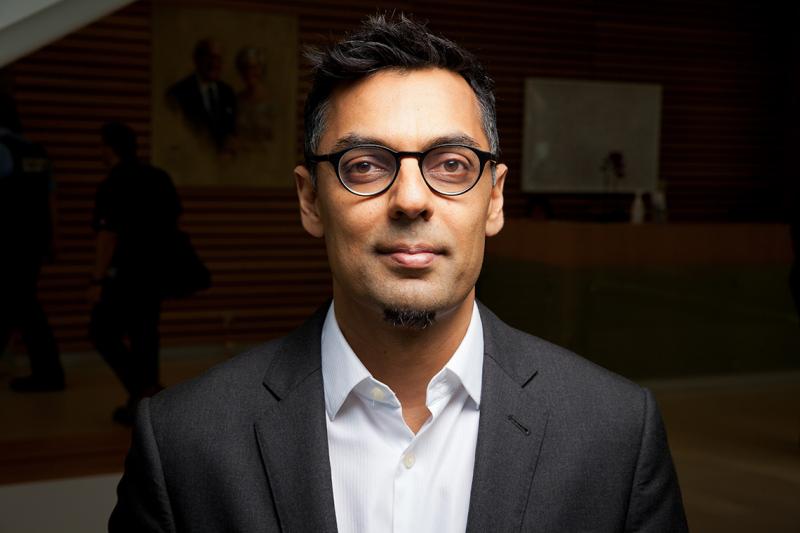 Portrait of Kamran Khan smiling slightly in an indoor lobby.