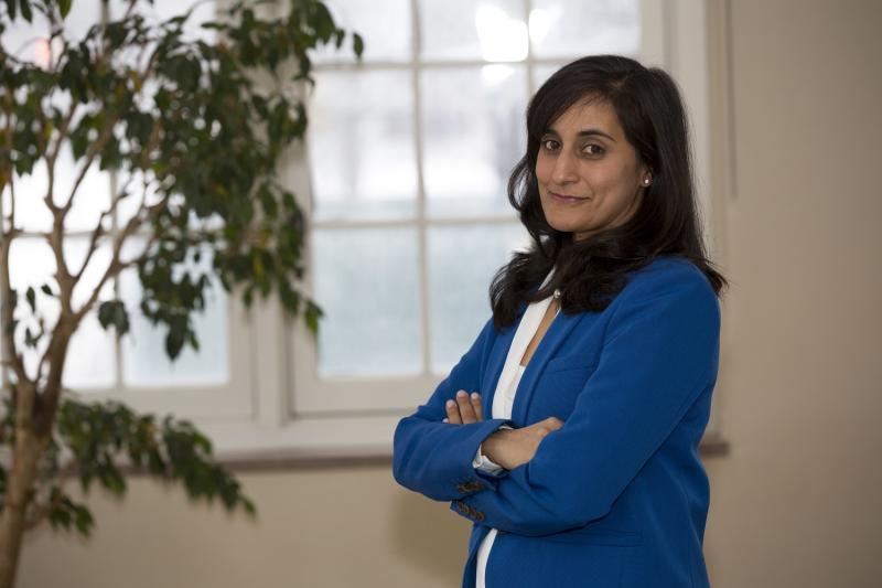 Anita Anand smiles as she stands indoors by a window.