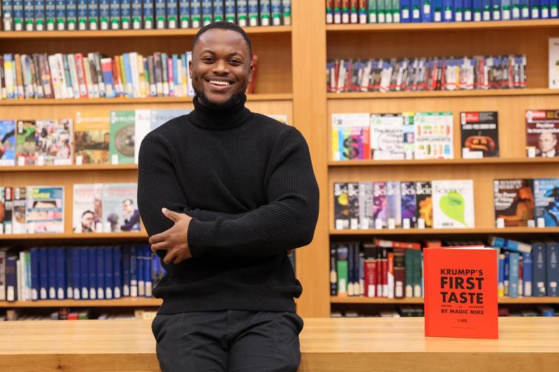 Michael Gayle smiling and standing in front of bookshelves