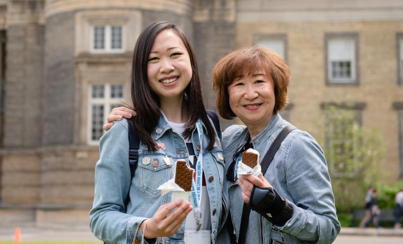 Two alumni posing together with ice cream in their hands.