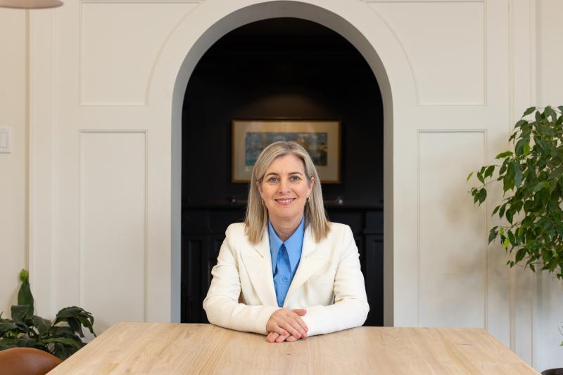Melanie Woodin smiles while sitting behind a desk.