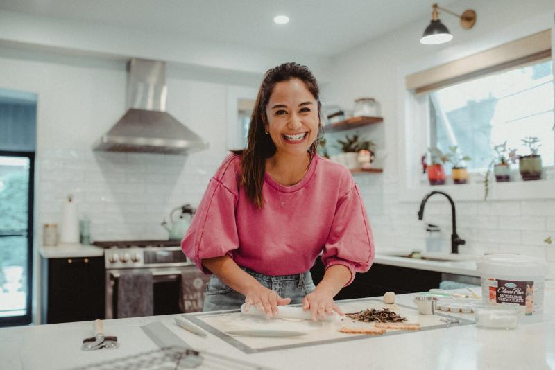 April Julian laughs as she rolls out pastry in a sunny home kitchen.