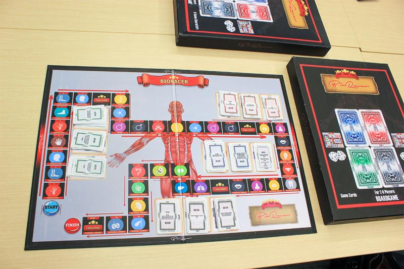 The BioRacer board game laid out on a table. Piles of cards match symbols pictured along a winding path on the game board.