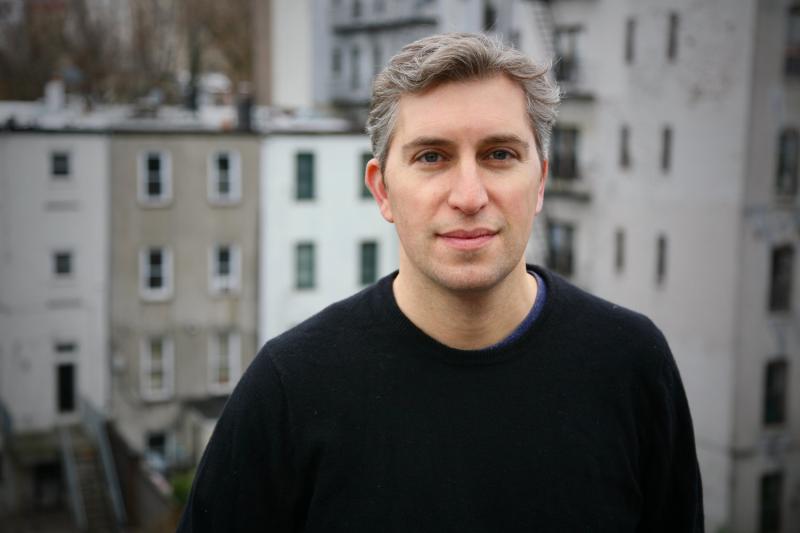 Andrew Blum standing outside with houses in the distance