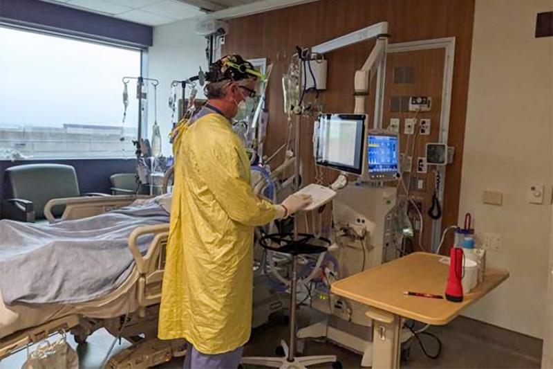 Marco Caminiti, wearing full protective equipment, accesses a console in an intensive care room.