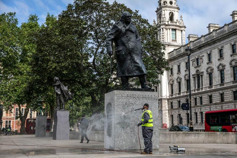 A worker uses a power hose to clean graffiti from the base of a statue of Sir Winston Churchill in London, U.K.