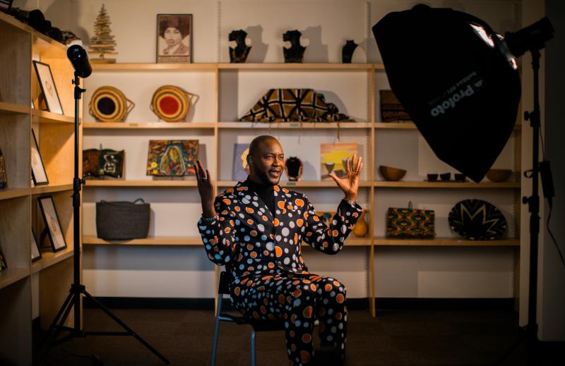 A Black man sitting in a chair and talking expressively