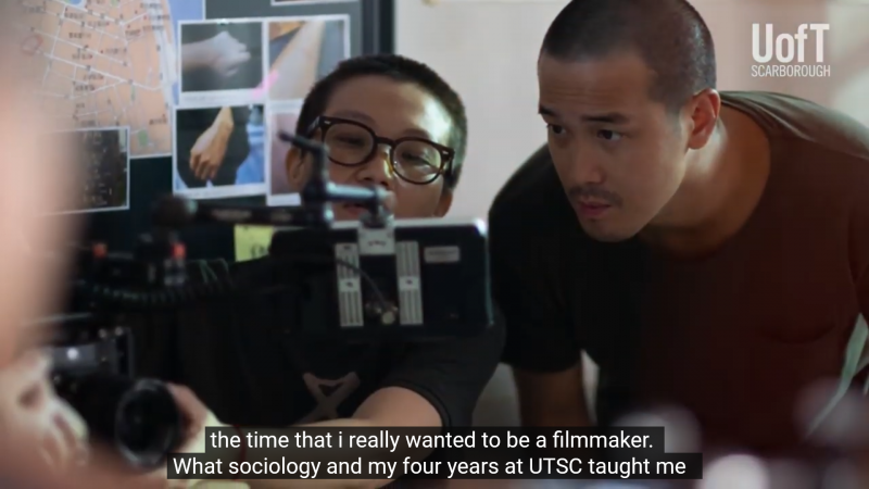 In a still from a video, Derek Tsang looks into the viewfinder of a camera.