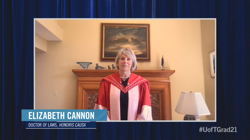 Elizabeth Cannon, wearing her academic robes and hood, speaks on video in a room with an elaborate fireplace.