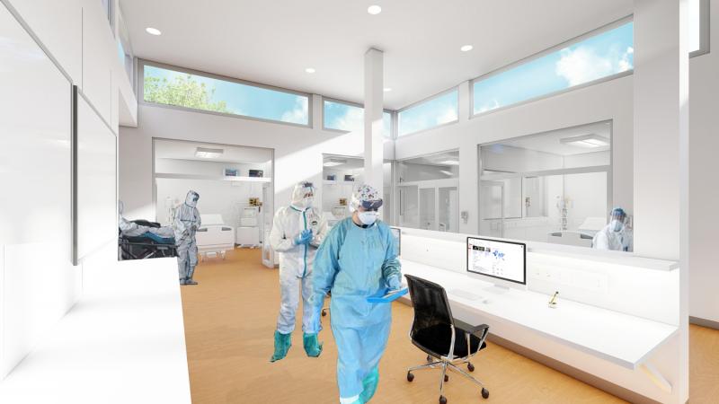 Workers in protective clothing walk down an open hallway lit by overhead windows.