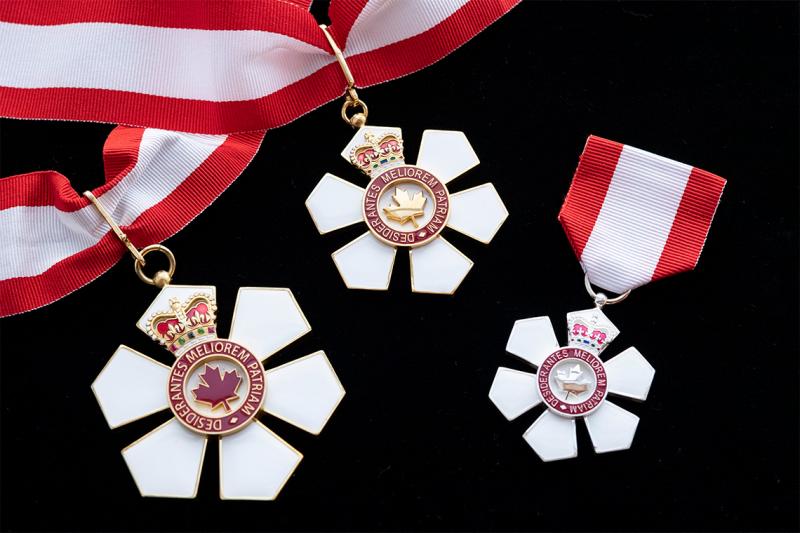 The Order of Canada medal is shaped like a six-petalled flower with a maple leaf centre, hanging from a red and white ribbon.