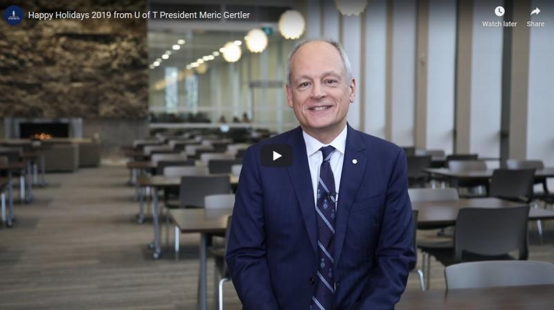 Meric Gertler smiles as he stands in a library reading room in a scene from his holiday video.