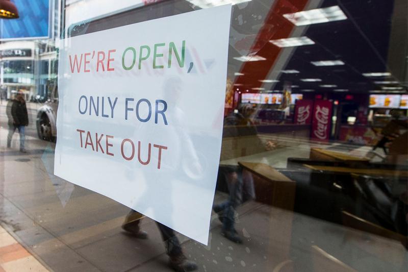 A sign in a restaurant window reads: We're open, only for takeout.