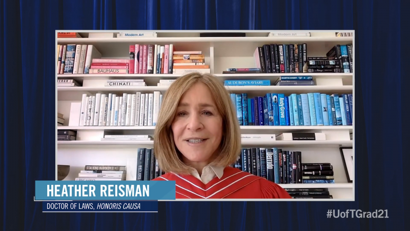 Heather Reisman, wearing academic robes, speaks on video in front of a bookcase of books arranged by colour.