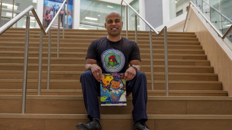 A man seated on a staircase holding a book