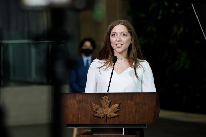 Lana El Sanyoura talks at a podium emblazoned with a carved wooden maple leaf.