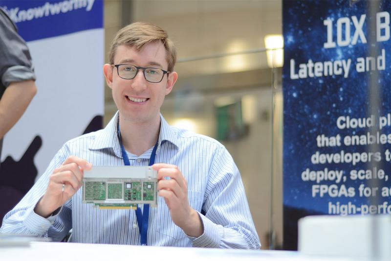 Andrew Canis smiles as he holds up a computer circuit board.