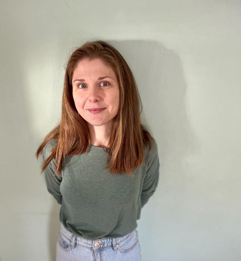 A portrait of Lucy standing in front of a wall