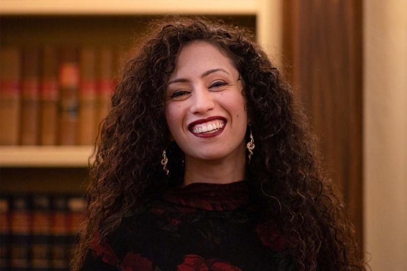 Mikaela Gabriel laughs happily, standing in a library.