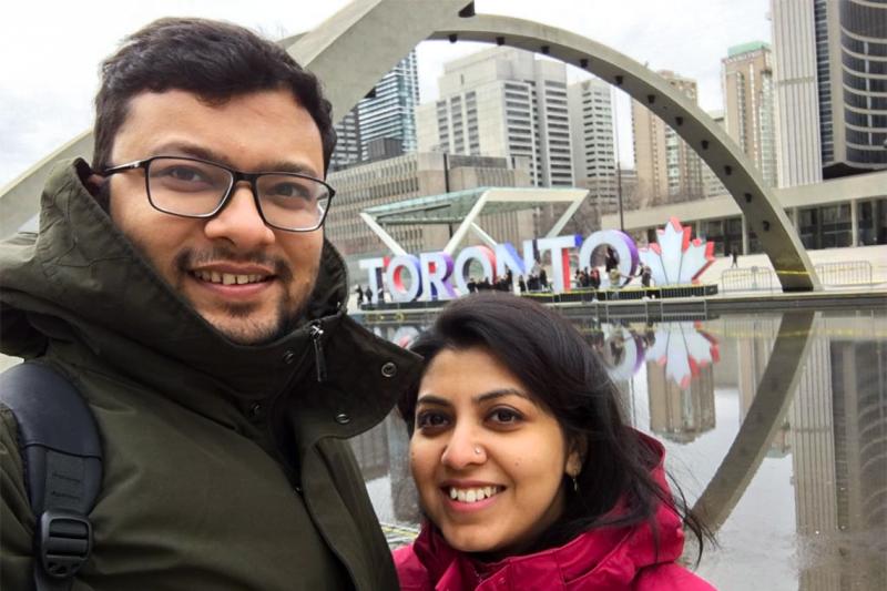 MD Nafizuzzaman and his wife smile as they take a selfie at City Hall, in front of the giant letters spelling TORONTO.