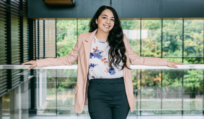 Anureet smiling and standing in front of a large bank of windows