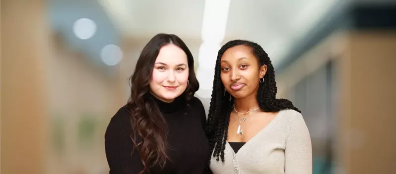 Two young women standing in front of a blurry background