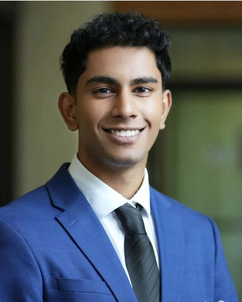 A portrait of Roshawn smiling in a smart blue suit