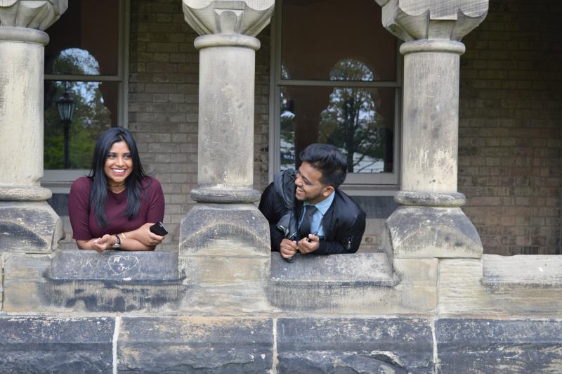 Trina and Kal look at each other playfully, standing in a stone building