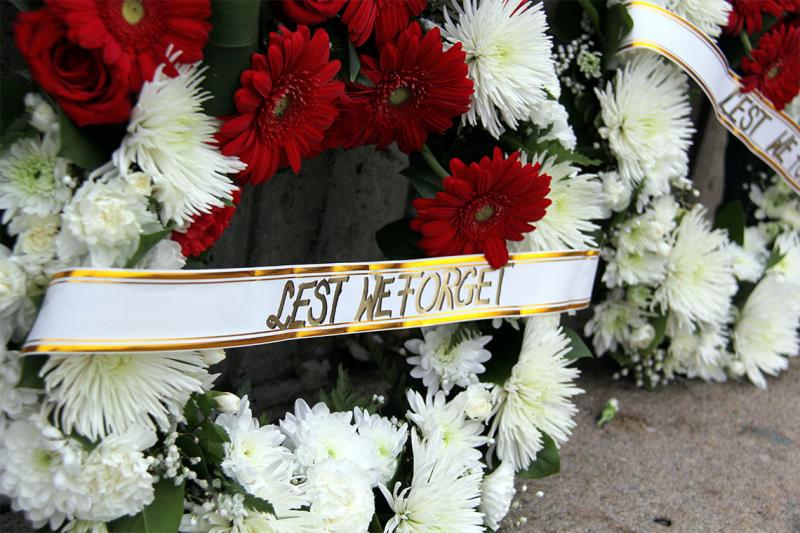 Bunches of flowers with a ribbon that reads, Lest we forget.