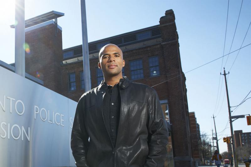 Akwasi Owusu-Bempah stands in front of a sign that reads Toronto Police Station.