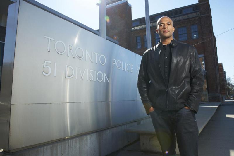 Akwasi Owusu-Bempah stands beside a Toronto police sign