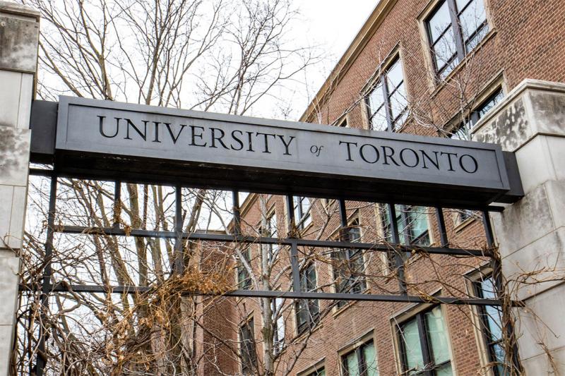 A metal sign reading, University of Toronto, bridges two stone pillars.