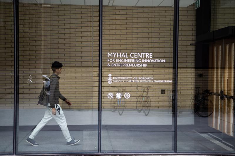 A young man with a backpack walks through the atrium of the Myhal Centre for Engineering Innovation & Entrepreneurship.