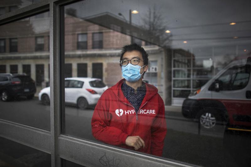 Albert Tai wears a mask and a Hypercare hoodie as he gazes thoughtfully out of a hospital window.