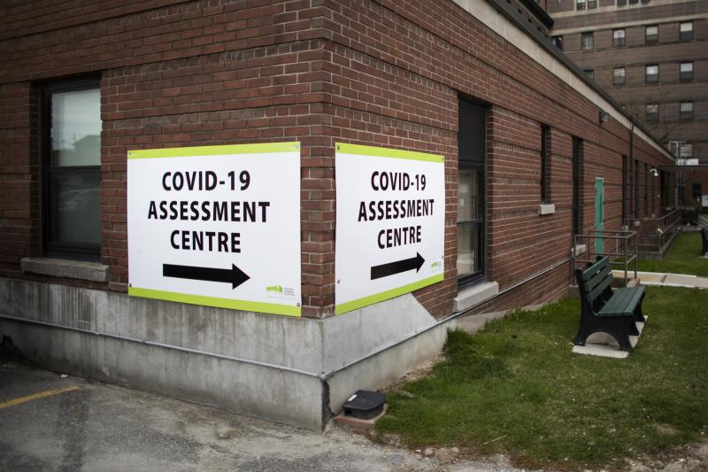 A sign on a brick building reads: COVID-19 Assessment Centre.