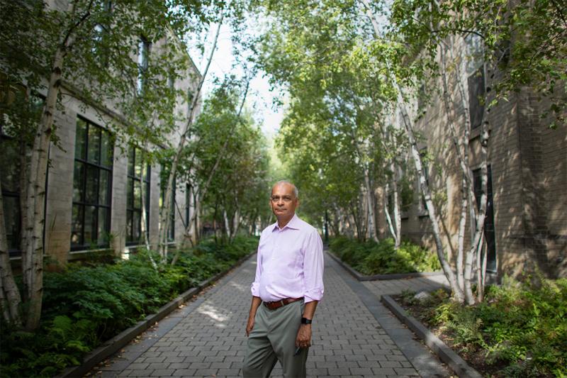 Vivek Goel looks serious as he stands in a leafy alley between buildings on the St. George campus.