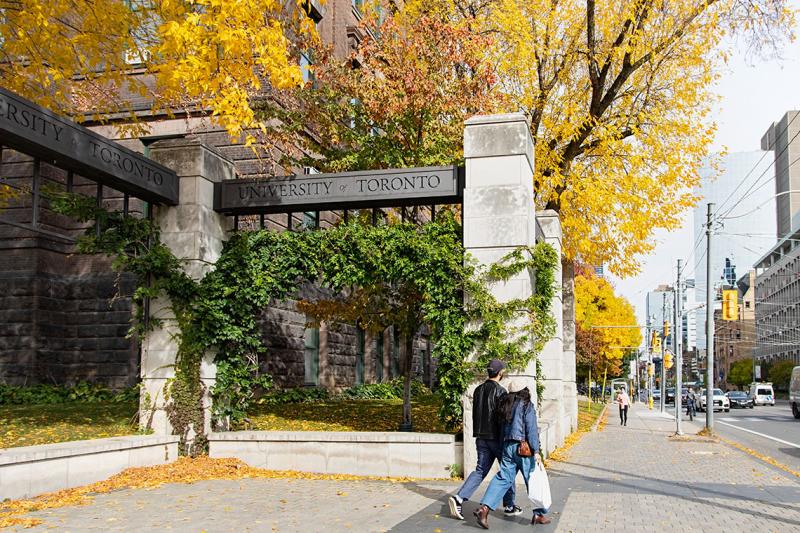 Metal beams (engraved with the words University of Toronto) rest across stone pillars to form U of T’s Alumni Gates. 