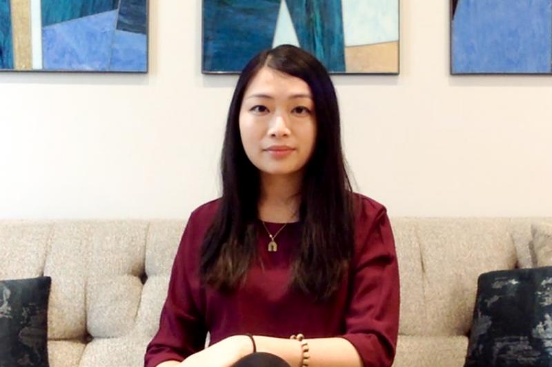 Vincci Liu looks serious as she sits on a sofa beneath colourful artworks.