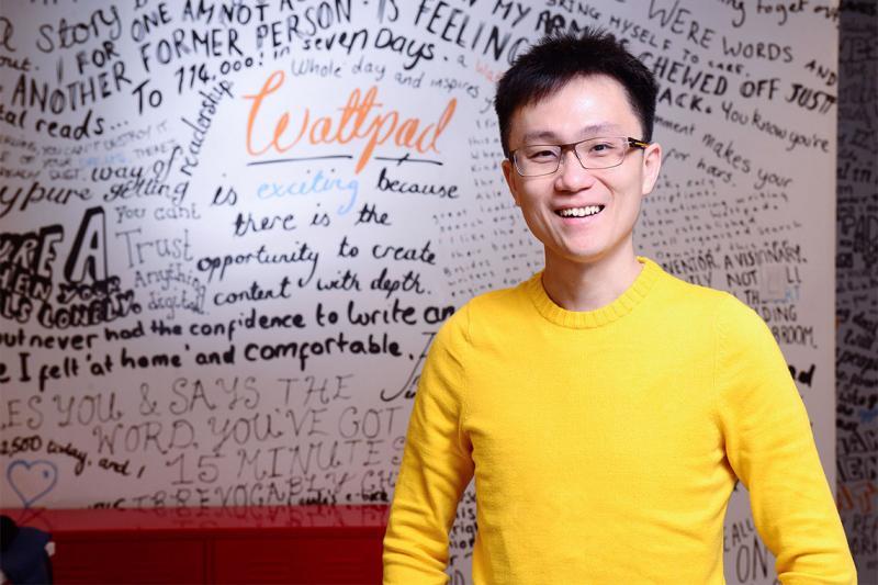 Allen Lau smiles while standing in front of a whiteboard scrawled with dozens of inspirational messages.