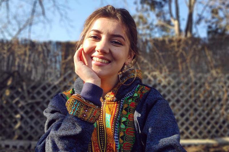 Portrait of Zarina Mamadbekova smiling and wearing a jacket with elaborately patterned trim.